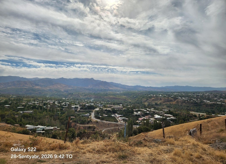 A mountainous landscape with a town in the valley, a winding road, and a clear sky. 5