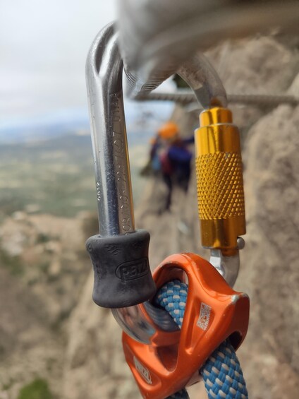 A close-up of a climbing carabiner with a rope and a metal hook. 1