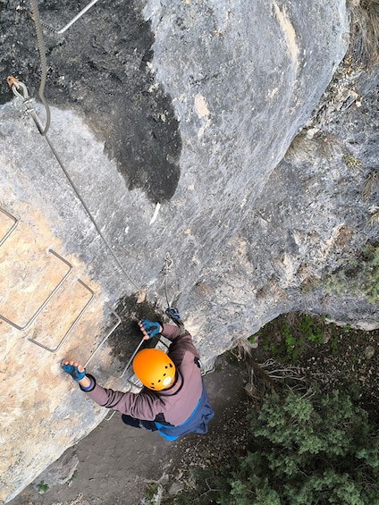 A person rappelling down a rocky cliff with safety harness and helmet. 3
