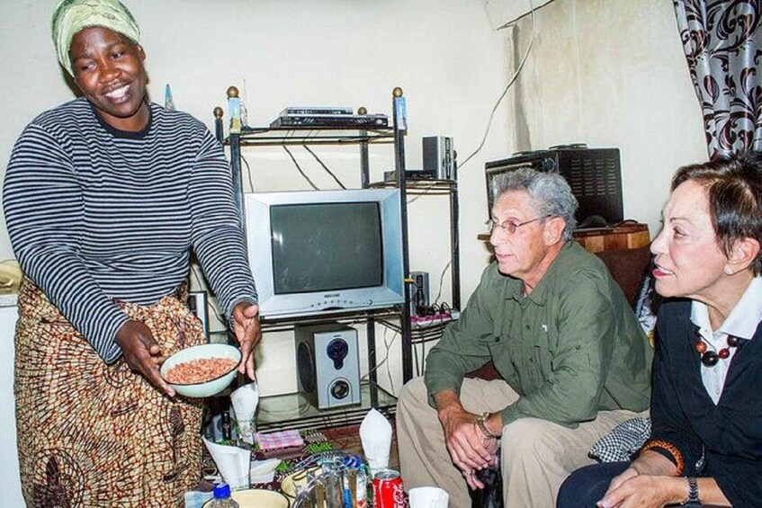 A person holding a bowl, a television, and a shelf with various items. 4