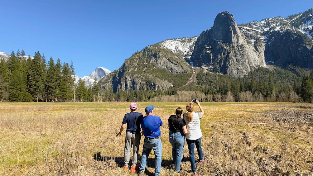 A group of people standing in a field with a mountain range in the background. 2