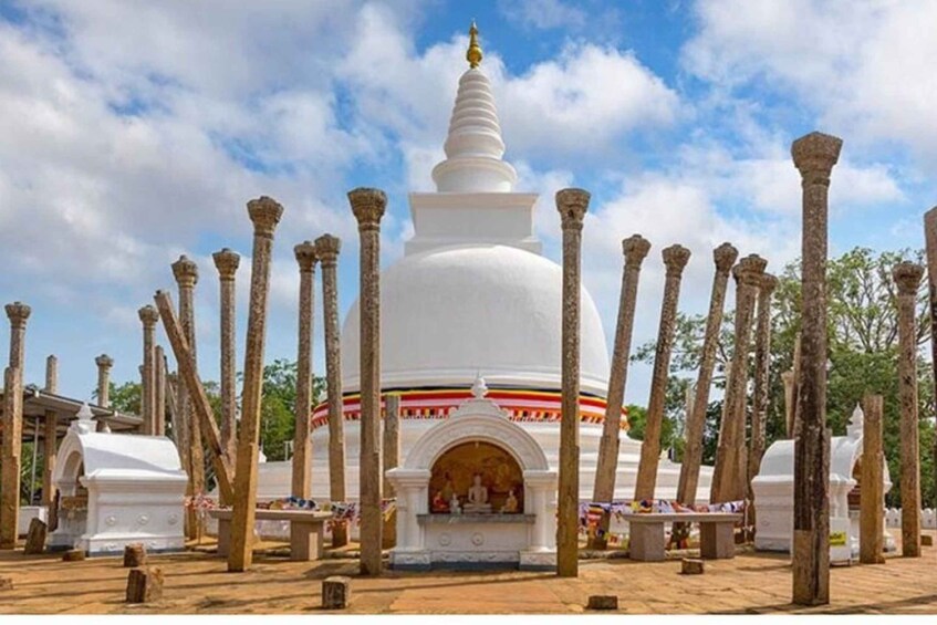 A white stupa surrounded by columns, with a clear sky above. 2