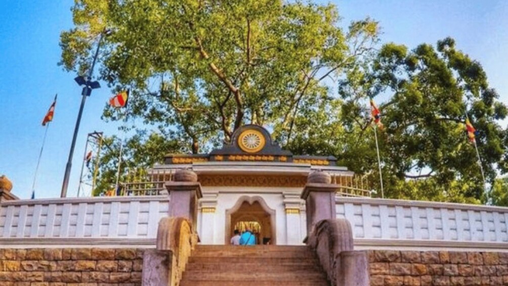A stone staircase leading to a temple entrance with a golden emblem above. 3