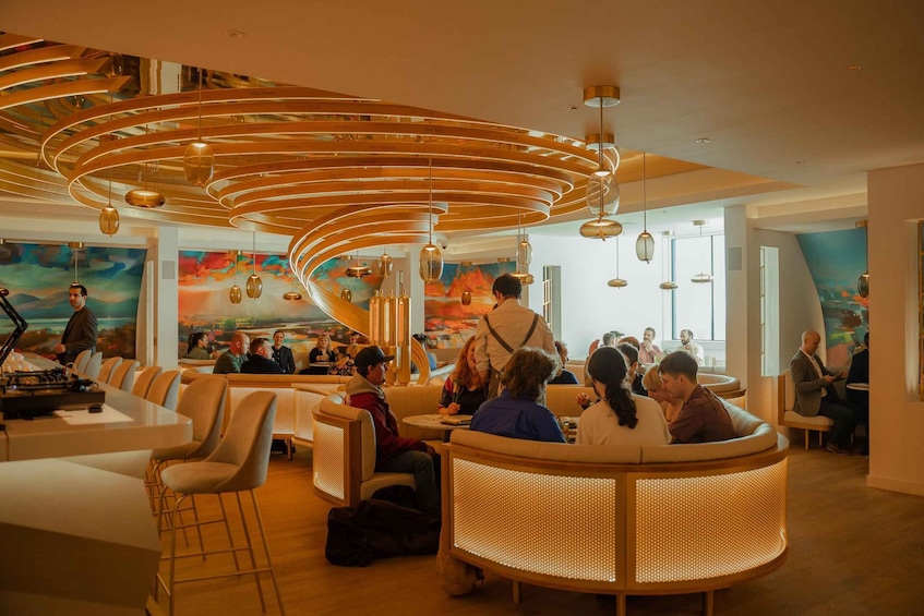 A modern lounge with circular seating, a DJ booth, and a mural. 4