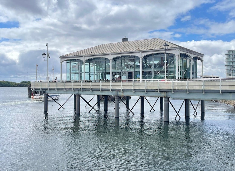 A glass-roofed pavilion on a pier over water. 2