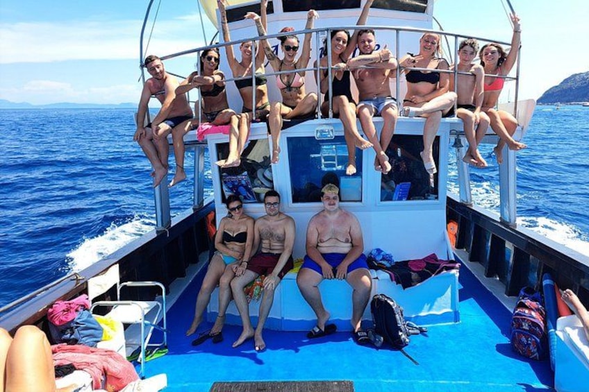 A group of people on a boat with a blue deck, surrounded by water. 3