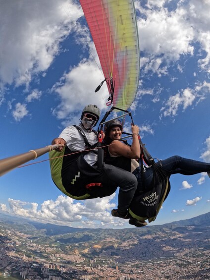Two people paragliding with a cityscape below. 2