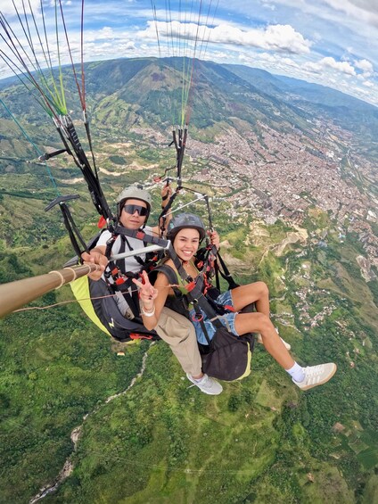 Two people paragliding over a mountainous landscape with a city below. 4
