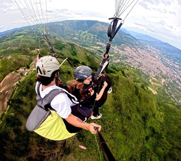 A person paragliding over a mountainous landscape with a city in the distance. 5