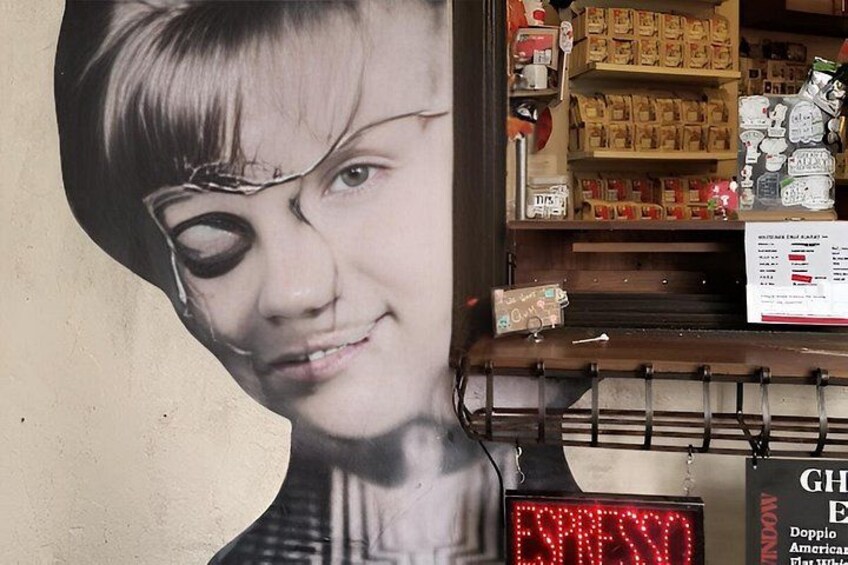 A wall with a portrait and a sign that reads 'GH Doppio American Whiskeys.' 1