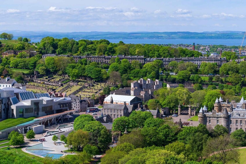 A historic town with castle ruins, a modern building with solar panels, and a body of water in the distance. 2