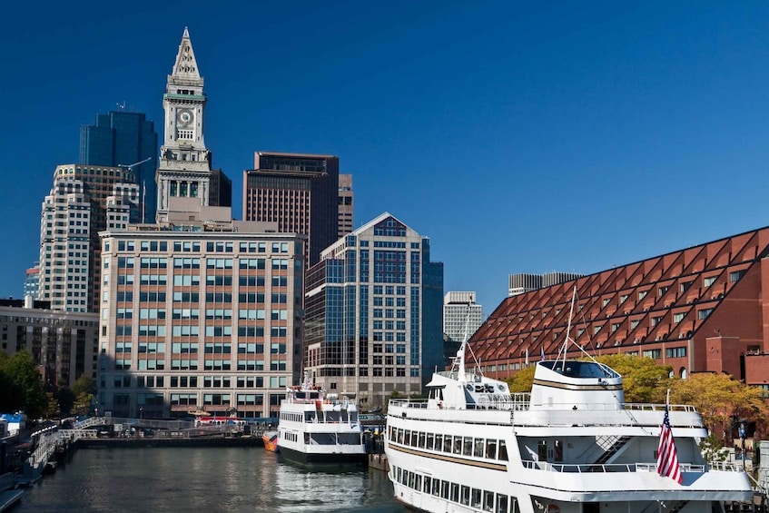 A river with two boats, a city skyline with a clock tower, and modern buildings. 3