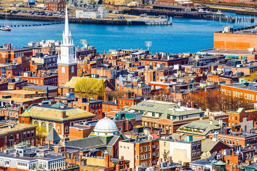 A densely packed urban area with historic buildings, a prominent church steeple, and a waterfront. 4