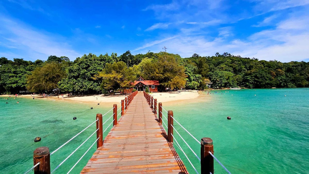 A wooden pier leading to a small building on a tropical beach. 1