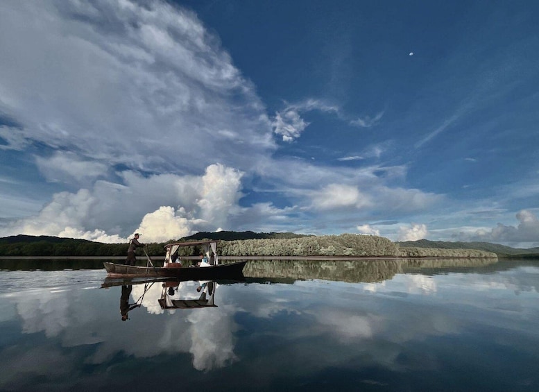 A calm lake with a boat, a clear sky, and a distant mountain range. 5