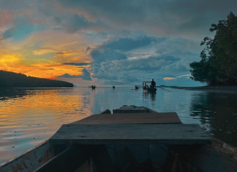 A sunset over a calm lake with boats and a dock. 2