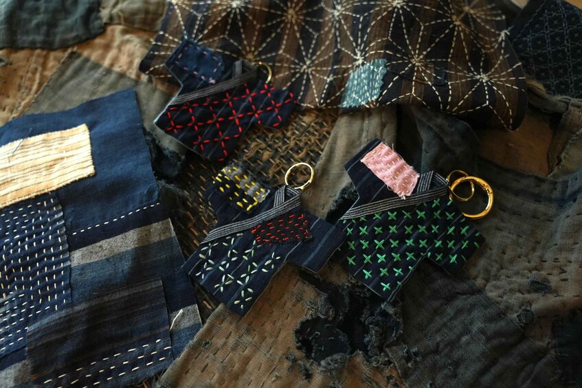 A collection of intricately embroidered fabric pieces with various patterns and colors, laid out on a textured surface. 1