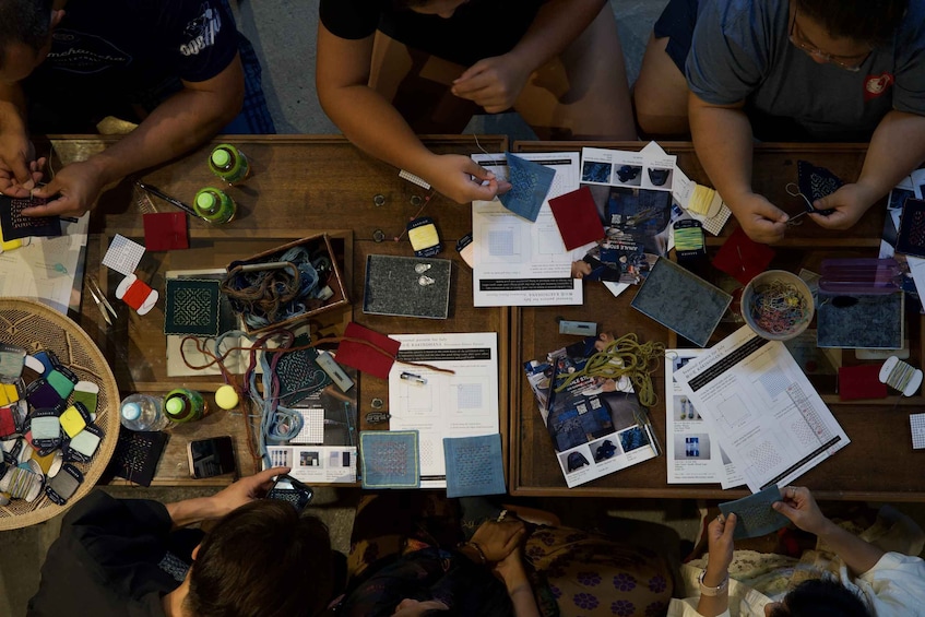 A group of people engaged in a craft activity, surrounded by various crafting materials and tools. 2