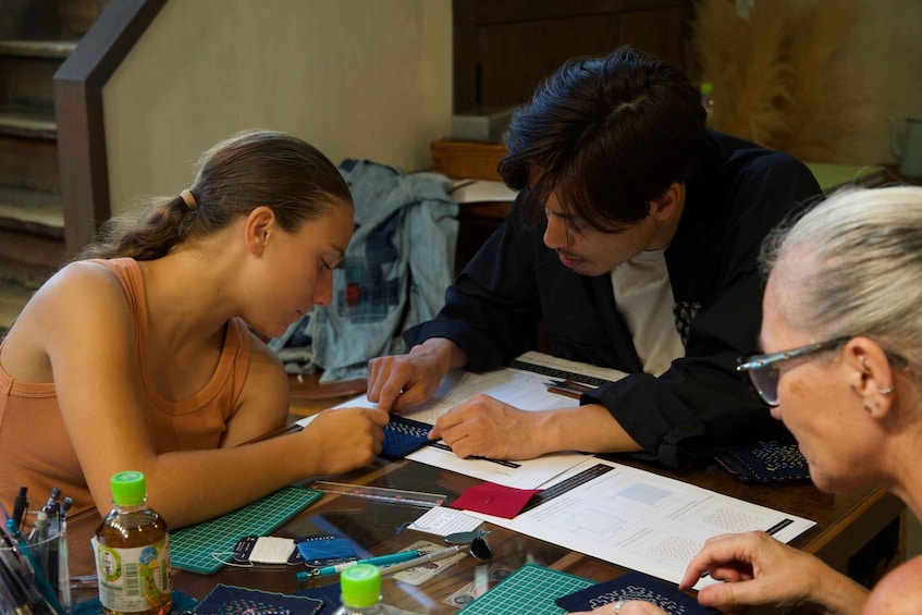Three people at a table with papers, calculators, and a bottle. 4