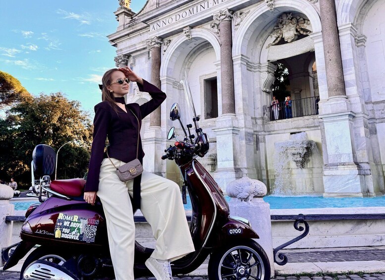 A person sitting on a scooter in front of a historic building with columns and a fountain. 1