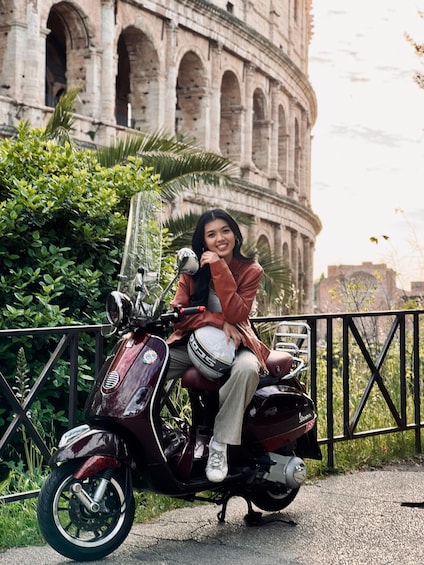 A person sitting on a vintage scooter in front of the Colosseum. 2