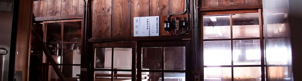 A wooden interior with a window, a sign with Japanese text, and a mechanical device. 5