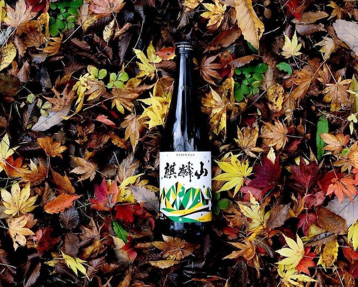 A bottle with a label on a bed of autumn leaves. 1