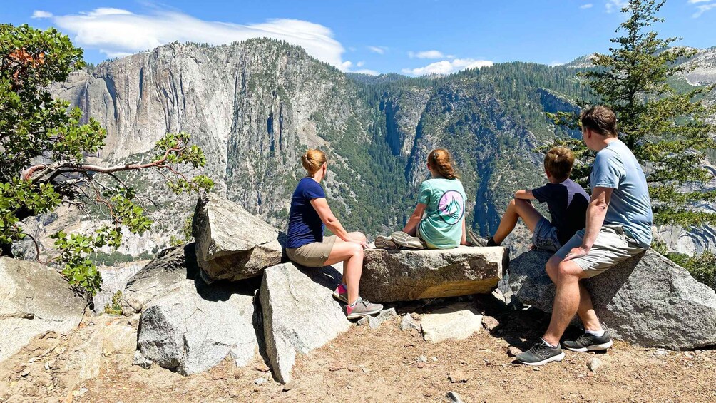 A group of people sitting on rocks overlooking a mountainous landscape. 4