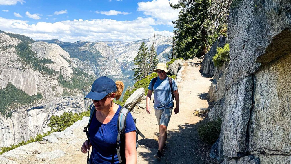 Two hikers on a rocky trail with mountainous scenery in the background. 2