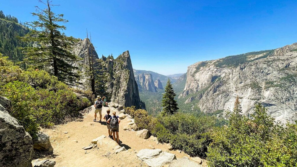 A group of hikers on a rocky trail with a mountainous landscape in the background. 5