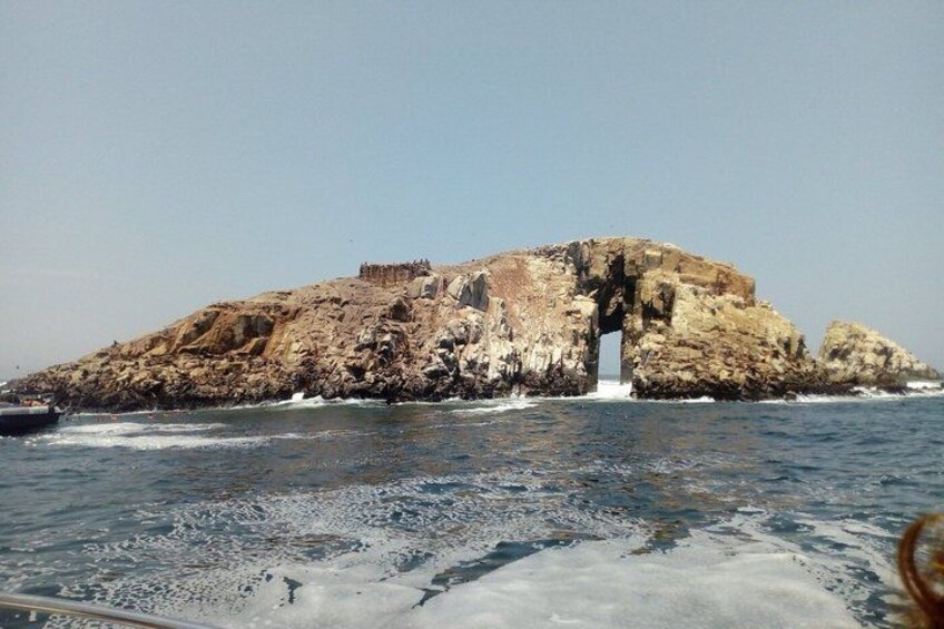A rocky island with a cave entrance surrounded by water. 1