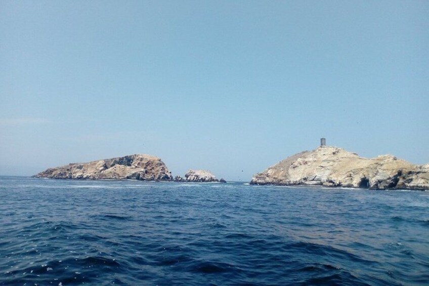 A calm sea with two rocky islands, one with a small structure on top. 5