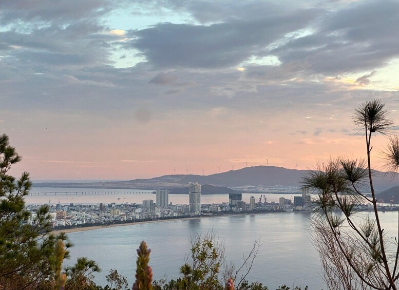 A coastal cityscape with a bridge, wind turbines, and a sunset. 4