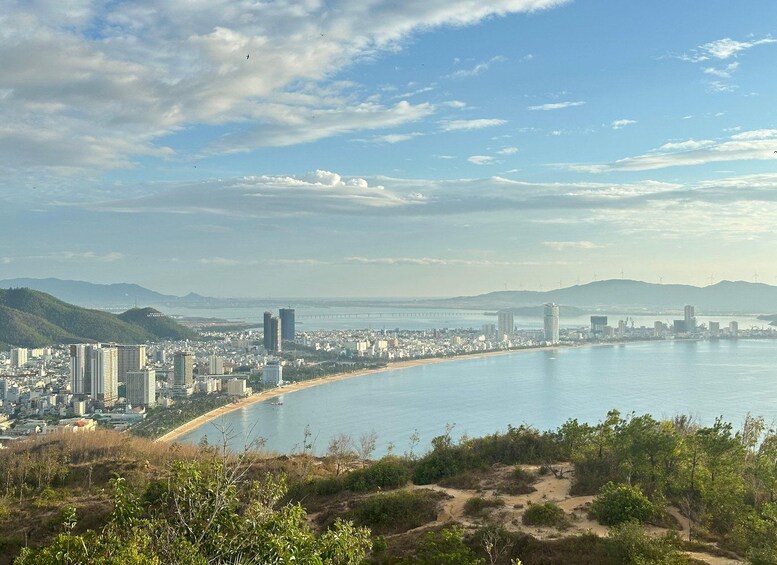 A coastal cityscape with a beach, a bridge, and distant mountains. 2