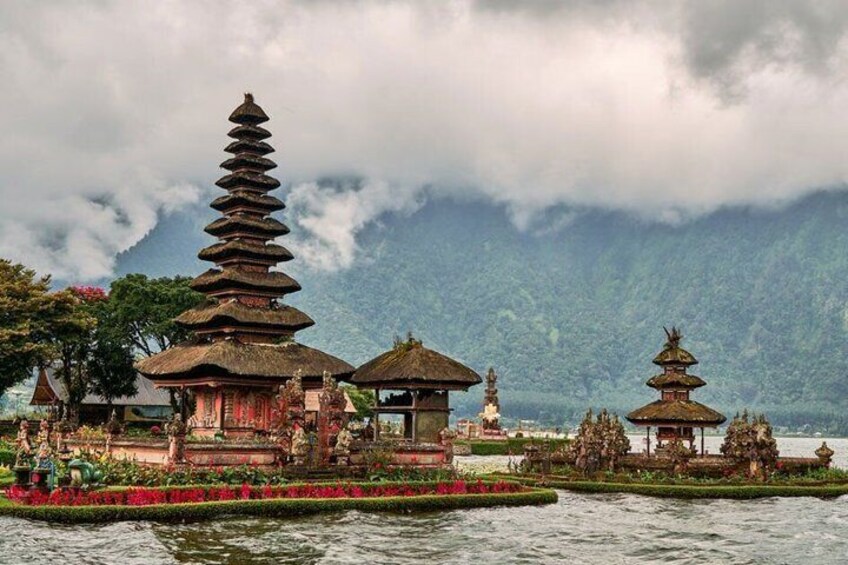 A traditional Balinese temple with tiered roofs, a lotus pond, and a mountainous backdrop. 4