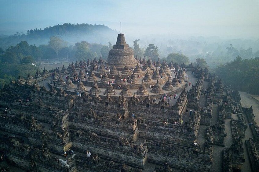 An ancient temple complex with multiple structures, surrounded by a forested area. 2