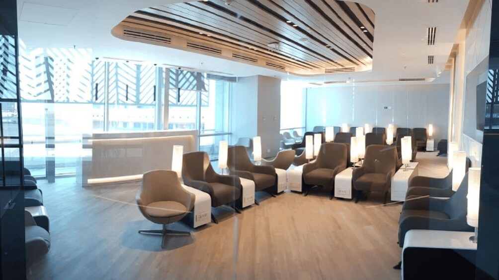A modern waiting area with rows of chairs, a reception desk, and large windows. 2