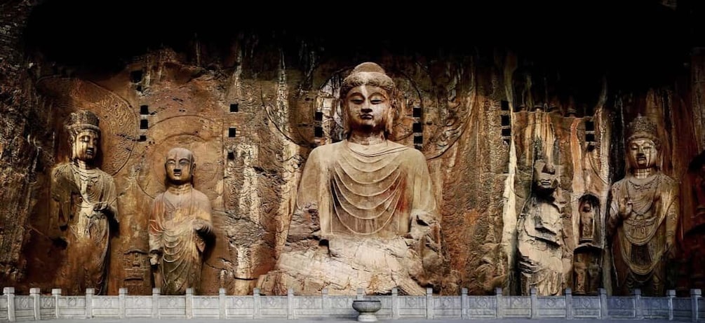 A large Buddha statue surrounded by smaller statues in a cave. 1