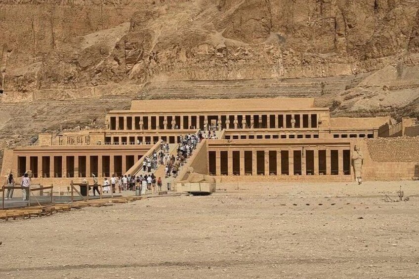 Un templo egipcio antiguo y grande con una larga escalera que lo conduce, rodeado de paisaje desértico. 2