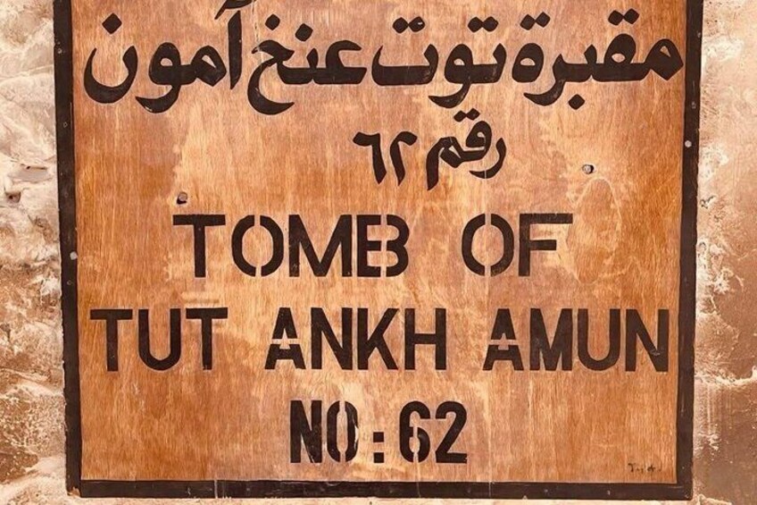 Un cartello di legno con testo in arabo e inglese, che indica 'TOMB OF TUT ANKH AMUN NO:62'. 4