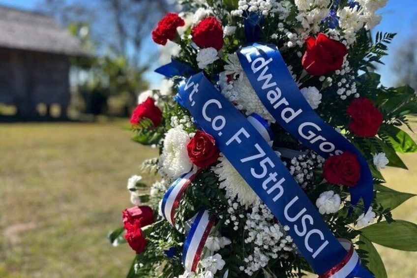 A memorial wreath with red and white flowers and a ribbon that reads 'Edward Gross Co. F 75th USCI.' 1