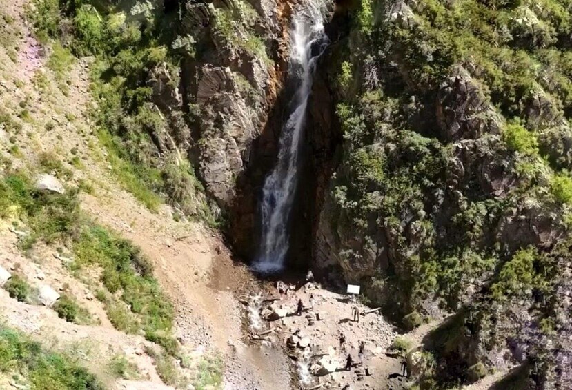 A waterfall cascading down a rocky cliff surrounded by greenery. 2
