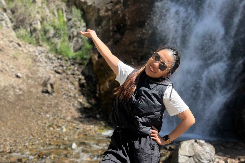 A person standing in front of a waterfall with a rocky landscape. 1