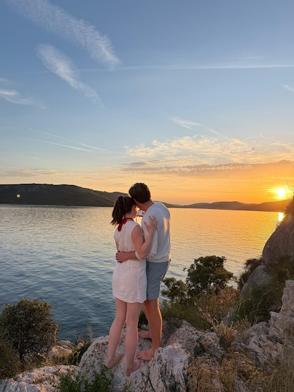 A couple embracing on a rocky lakeside at sunset. 2