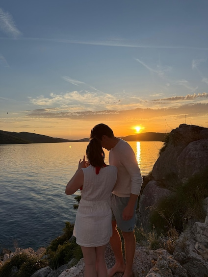 A couple standing by a lake at sunset with the sun reflecting on the water. 4