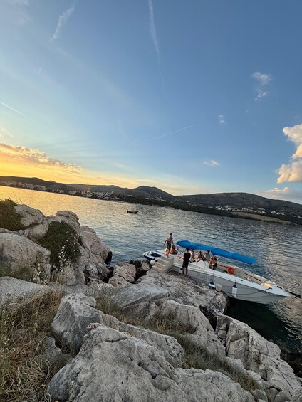 A rocky shoreline with a boat docked near the water's edge, a clear sky, and distant hills. 3