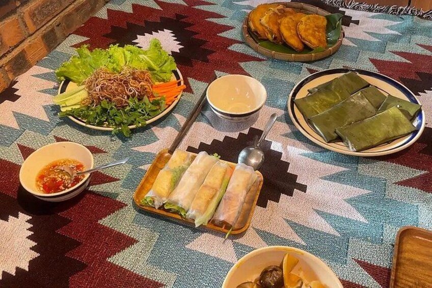 Une table où l’on trouve divers plats, notamment des rouleaux de printemps, une salade et des tamales. 4