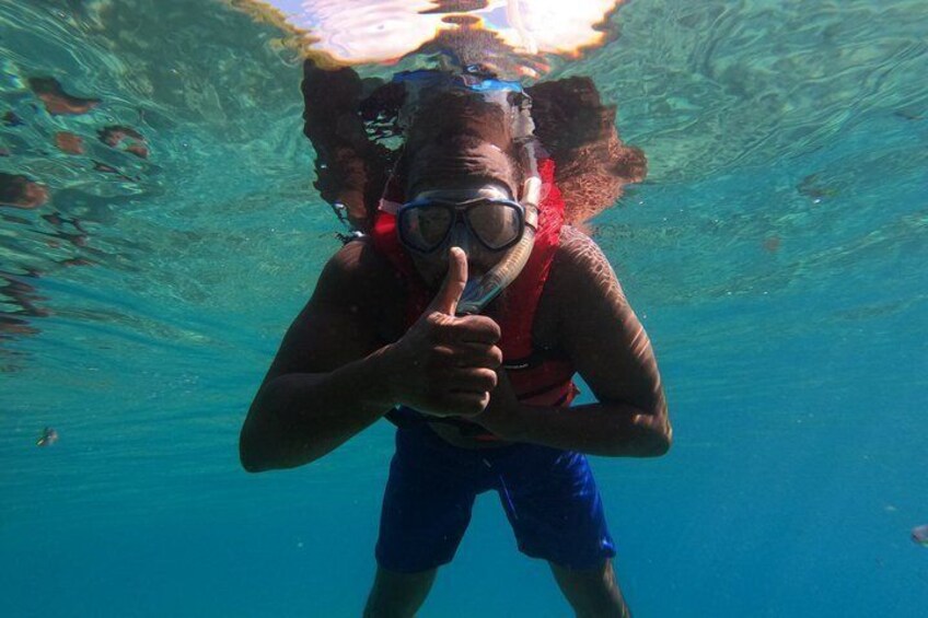 A person underwater, wearing a snorkel and mask, pointing towards the camera. 5