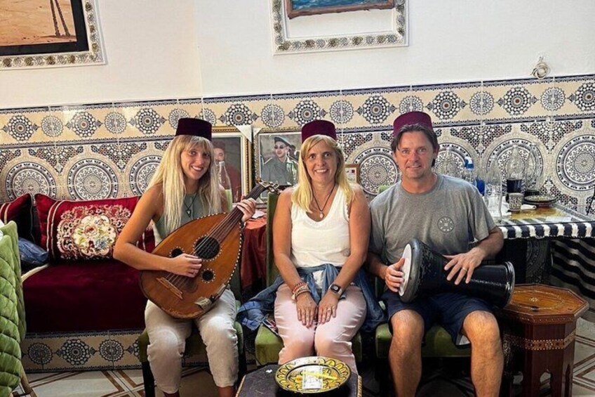 Three people sitting on a couch with a patterned wall in the background. 3