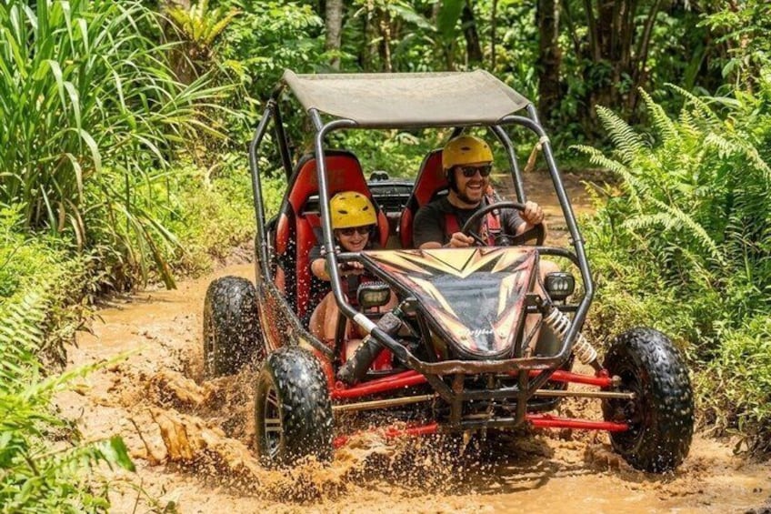 A vehicle navigating a muddy path in a forested area. 2